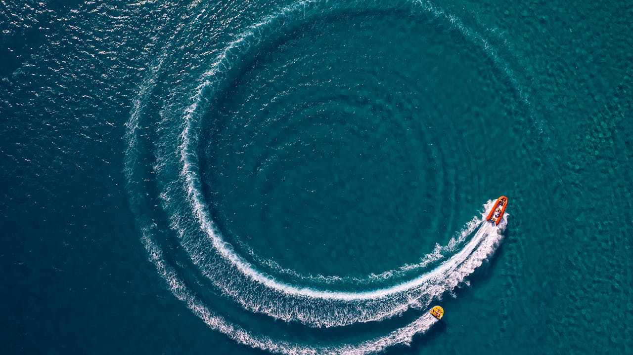 Dynamic aerial shot of a motorboat creating waves in azure waters of Alaçatı, İzmir.